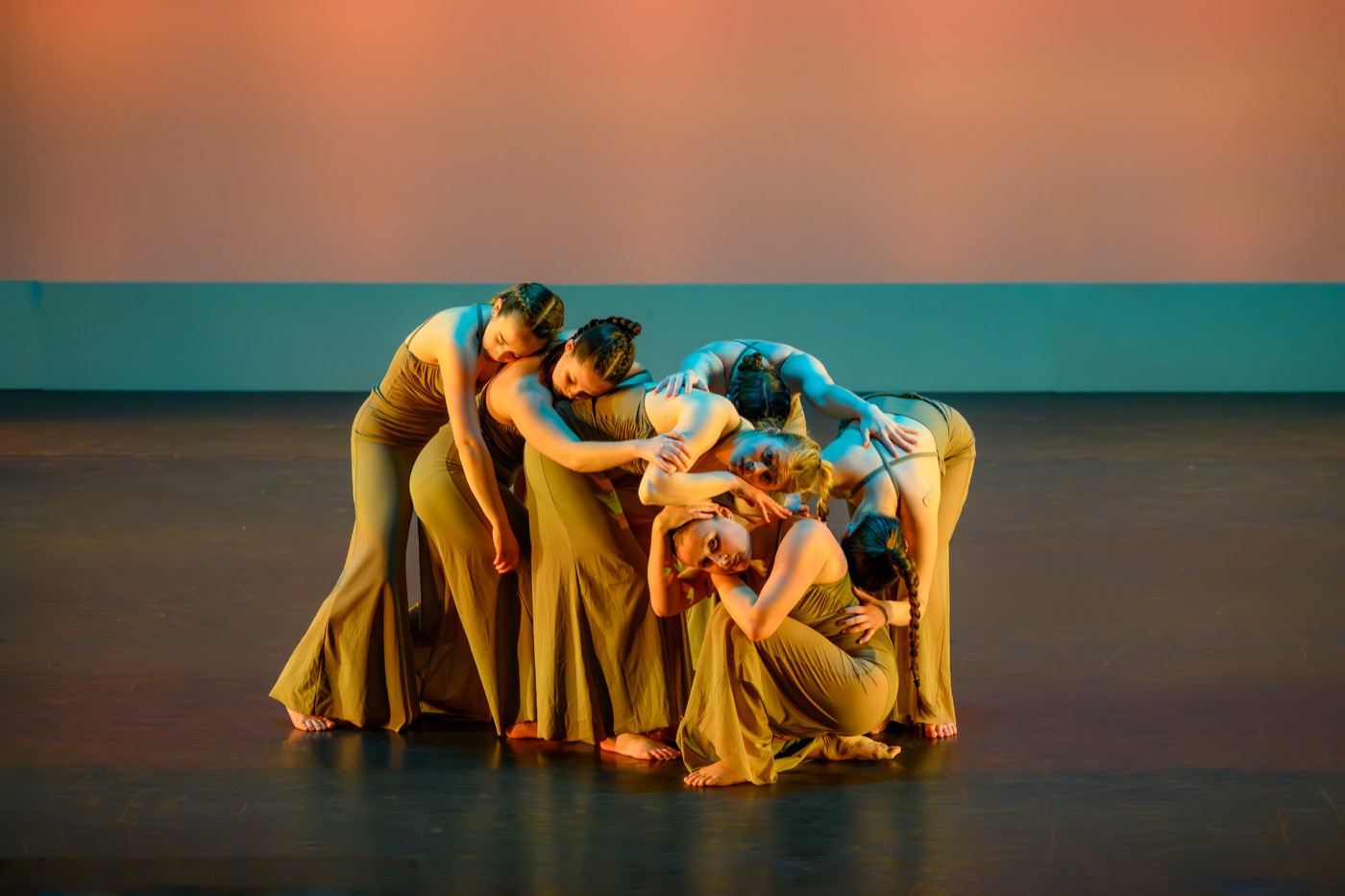 Dance ensemble performing on stage under colorful theatrical lighting