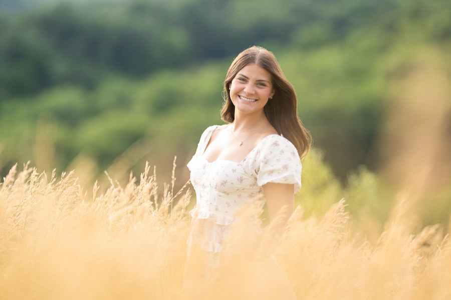 Senior portrait in a sunlit field of tall grass